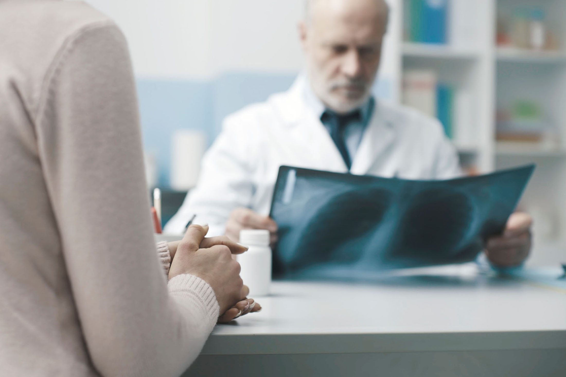 Doctor reviewing patient X-ray for diagnosis and medical bill funding services.