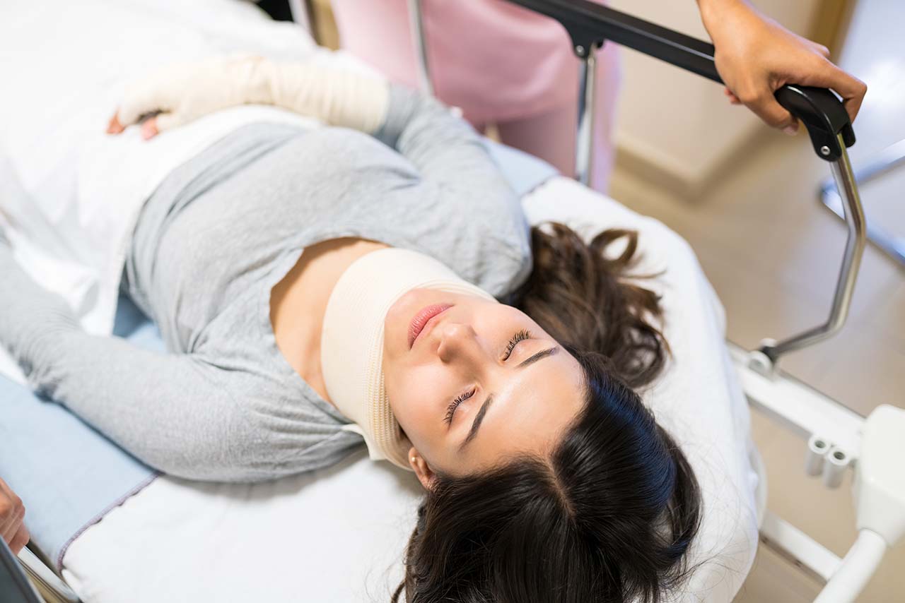 Patient on a stretcher with neck brace needs injury case funding