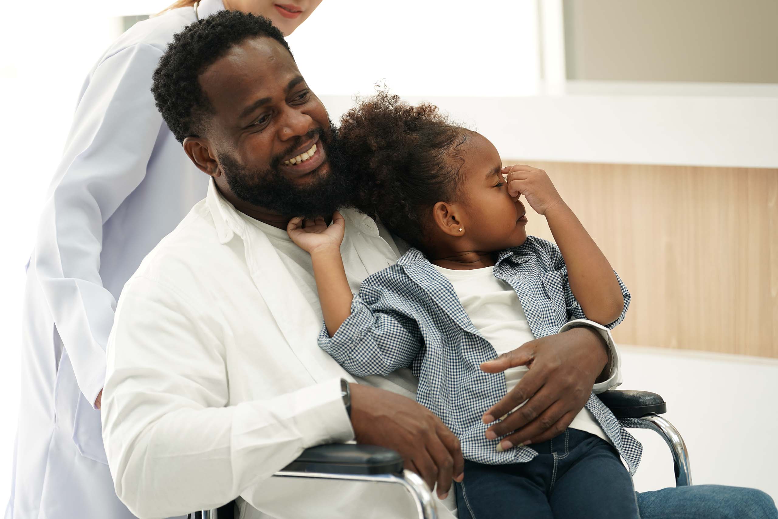 Father in wheelchair with child in hospital hall, highlighting the real-world impact of our MMB solutions.